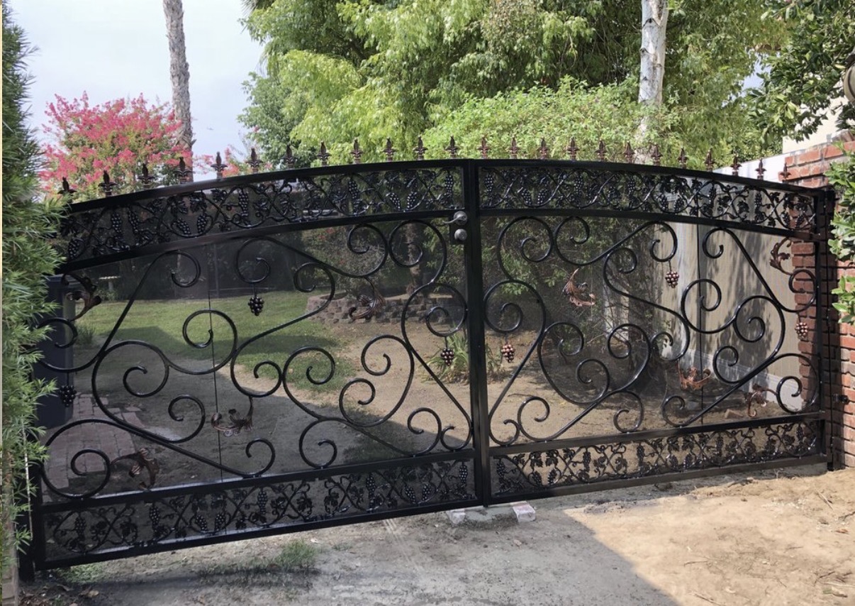 Ornate black iron driveway gate with grape vine details