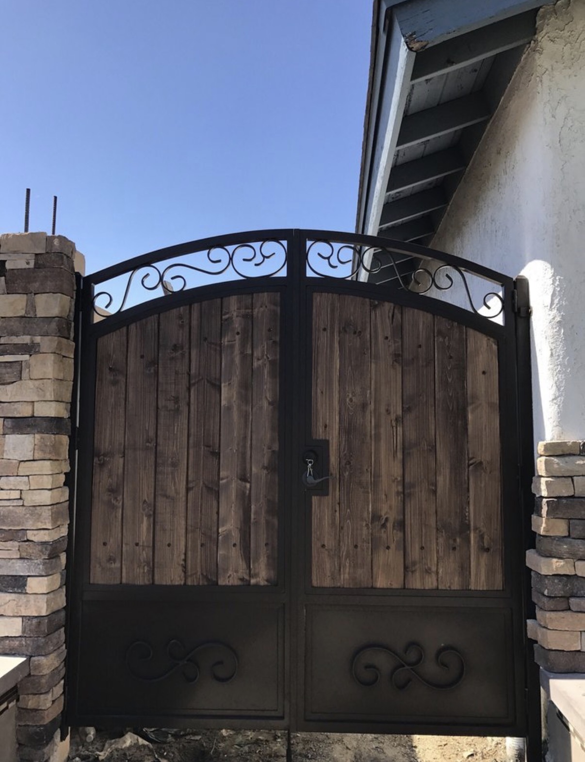 Arched wood and iron side gate with stone columns