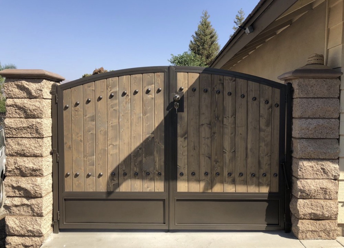 Rustic wood driveway gates with iron studs and arch