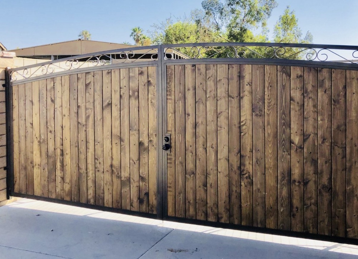Wood and iron driveway gates with arched scrollwork crown