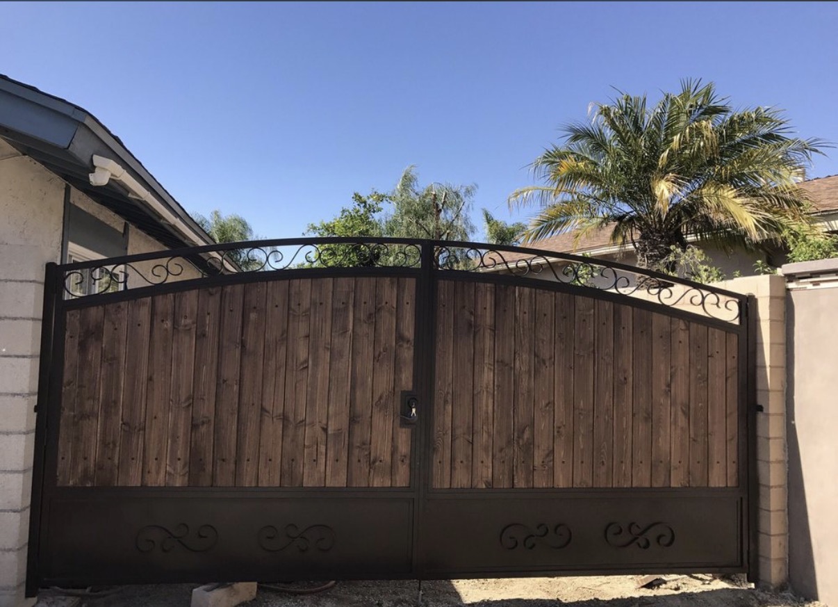Wood and iron arched driveway gate with scrollwork details