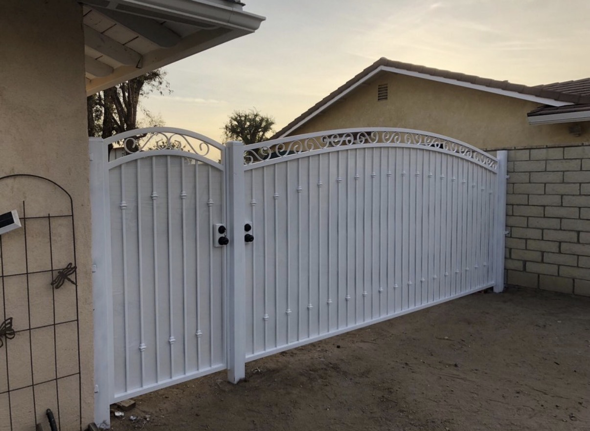 White vinyl driveway gate with iron scrollwork crown