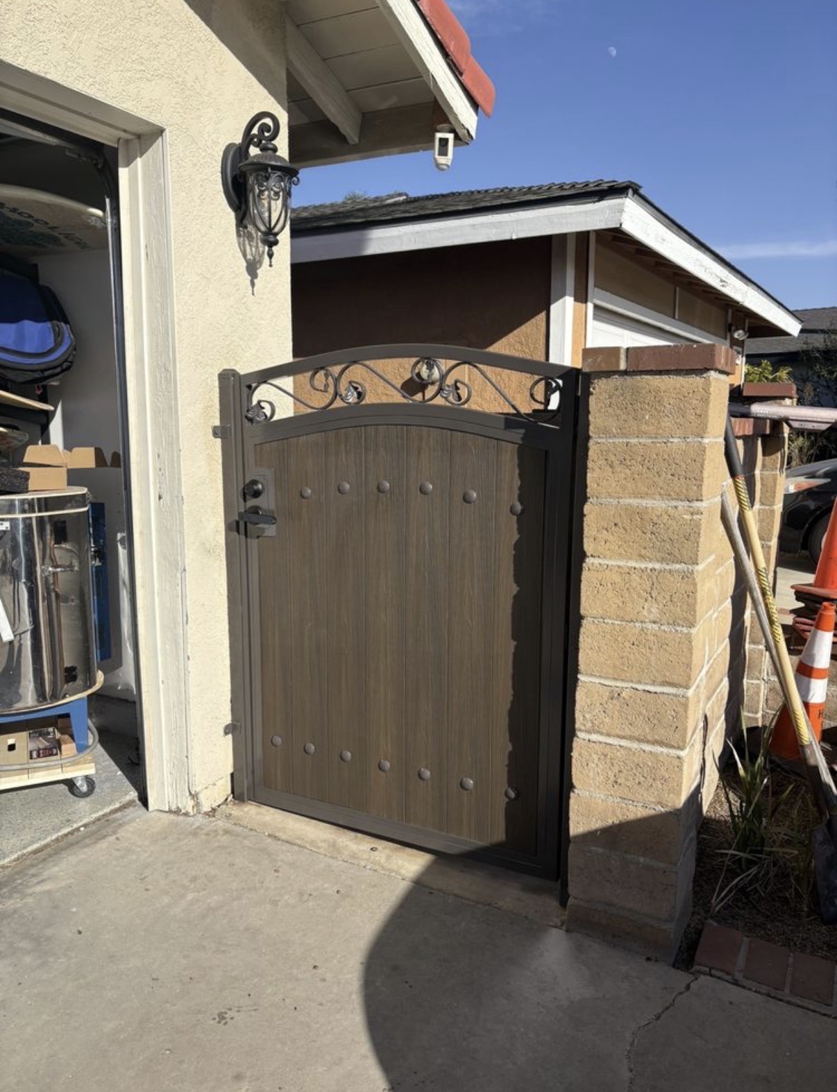 Wood-grain arched side gate with iron scrollwork crown and studs